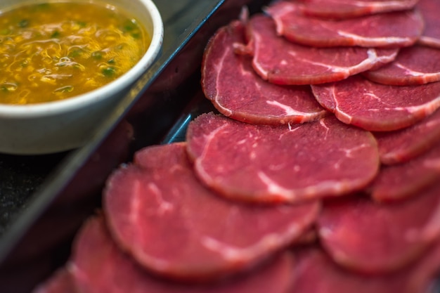 La carne cruda del manzo fa scorrere sul piatto con salsa barbecue al BBQ. ristorante a buffet con grill yakiniku