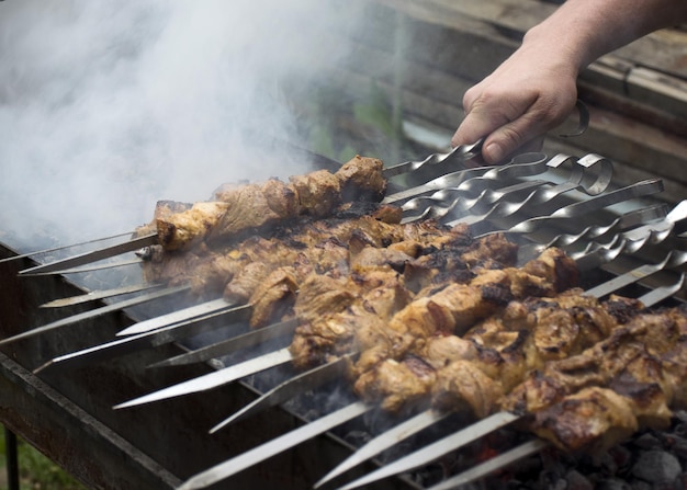 La carne cuoce sui carboni ardenti nel fumo Picnic in natura Il maiale viene fritto alla griglia