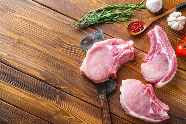 La carne suina cruda taglia con le erbe e le spezie con la mannaia americana della carne sullo spazio di legno di vista laterale del fondo per testo. Diagonale