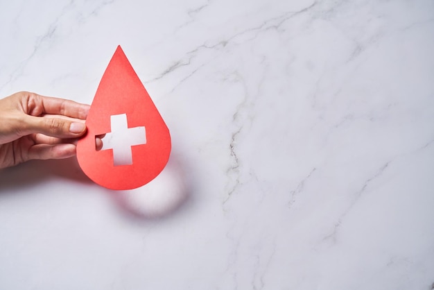 La carta della goccia di sangue ha tagliato la croce rossa della giornata mondiale del donatore di sangue per la trasfusione di sangue per dare il concetto della giornata dell'emofilia nel mondo del sangue