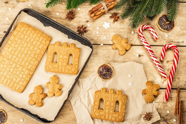 La casa di pan di zenzero di Natale e gli uomini di pan di zenzero. Design festivo tradizionale di Capodanno, processo di cottura. Fondo in legno vecchio, stile rustico, vista dall'alto