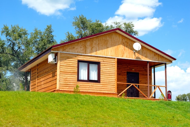 La casa in legno con prato sullo sfondo del cielo azzurro