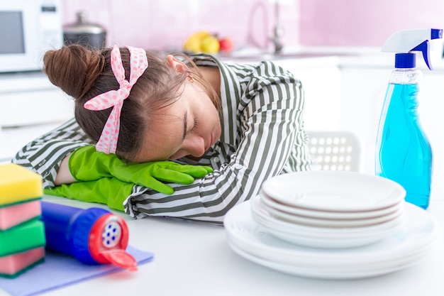 La casalinga stanca oberata di lavoro si addormentò e si riposò sul tavolo a causa della fatica delle pulizie delle pulizie di primavera e delle faccende domestiche difficili