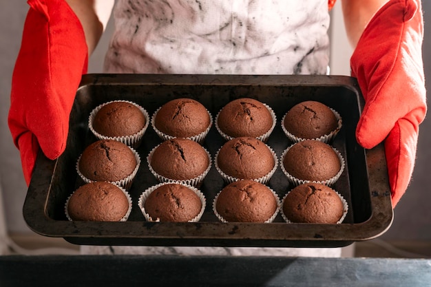 La casalinga tiene la teglia con i cupcakes caldi appena sfornati Muffin al cioccolato fatti in casa