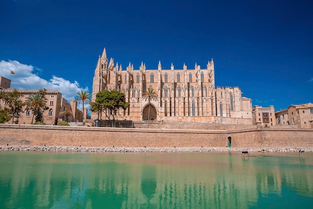 La cattedrale gotica di La Seu si riflette nell'acqua del canale contro il cielo blu in estate