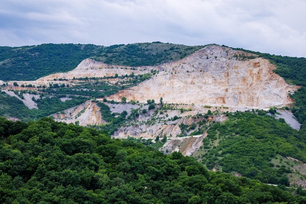 La cava naturale si trova vicino alla strada sullo sfondo dei Monti Rodopi e delle colline con foreste e vegetazione di montagna