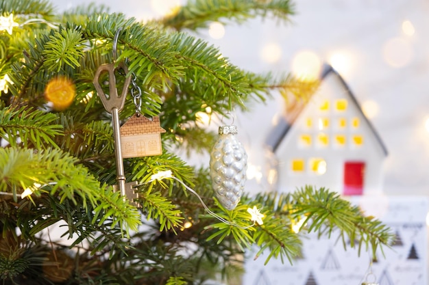 La chiave della casa con un portachiavi è appesa all'albero di Natale Un regalo per Capodanno Natale Progetto di progettazione edilizia trasferirsi in una nuova casa affitto ipotecario e acquisto di immobili Copia spazio