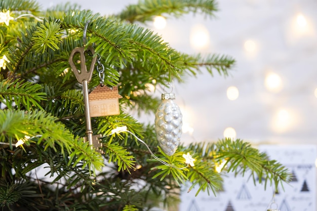La chiave della casa con un portachiavi è appesa all'albero di Natale Un regalo per Capodanno Natale Progetto di progettazione edilizia trasferirsi in una nuova casa affitto ipotecario e acquisto di immobili Copia spazio