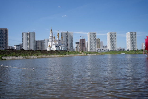 La Chiesa ortodossa russa sorge sulle rive del fiume sullo sfondo di case moderne.