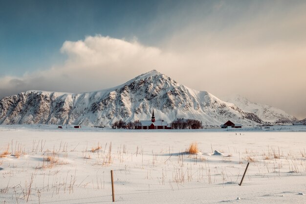 La chiesa parrocchiale rossa con la montagna innevata a Flakstad, Norvegia