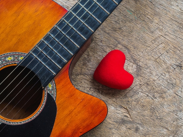 La chitarra e il cuore rosso su sfondo texture di legno