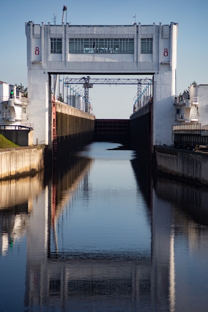 La chiusa del fiume viene riempita d'acqua per consentire il passaggio della nave. Chiusure per navi sul canale di Mosca. Organizzazione del traffico navale sul fiume. L'edificio della serratura si riflette nell'acqua.