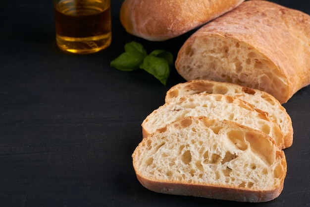 La ciabatta è un pane bianco italiano a base di farina di grano acqua sale lievito olio d'oliva su sfondo nero spazio copia