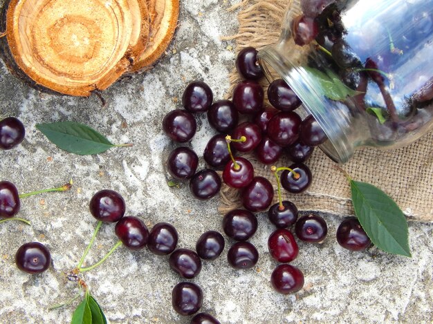 La ciliegia marrone matura fuoriesce da un barattolo di vetro sulla tela