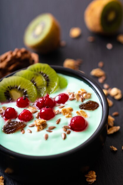 La ciotola variopinta della prima colazione del yogurt dell&#39;alimento sano fruttifica guarnizione con lo spazio della copia