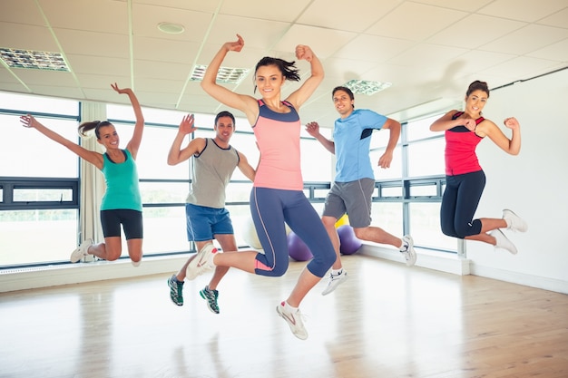 La classe di forma fisica e l&#39;istruttore che saltano nello studio di forma fisica