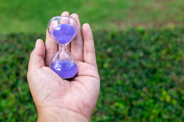 La clessidra che scivola tra le mani di un uomo in giardino che ricorda un passato nostalgico