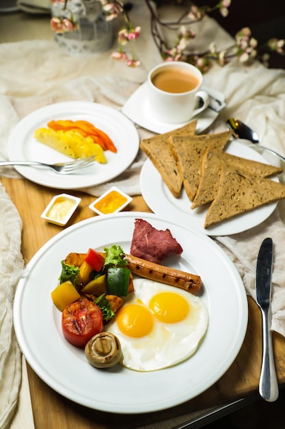 La colazione all'inglese con insalata di verdure comprende foglie di lattuga, patate, pomodori e carote con tè, caffè e melone dolce serviti sul tavolo con vista dall'alto, colazione sana