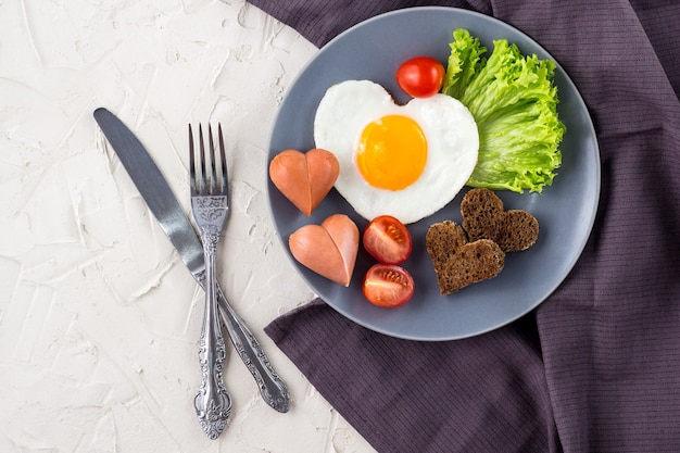La colazione di San Valentino con uova fritte a forma di cuore è servita su lastra grigia