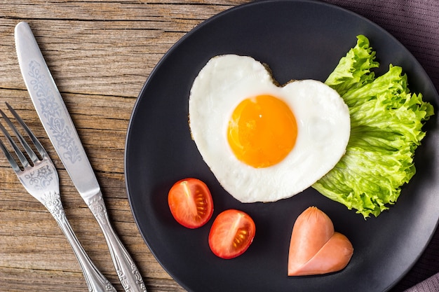 La colazione di San Valentino con uova fritte a forma di cuore è servita su lastra grigia