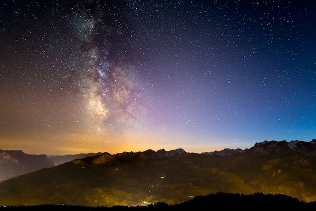 La colorata Via Lattea luminosa e il cielo stellato sulle Alpi francesi e il maestoso Massiccio degli Ecrins.