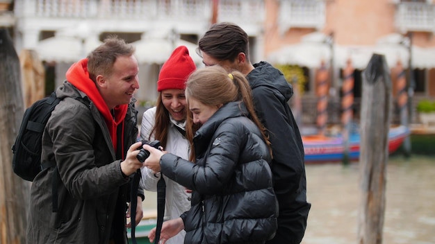 La compagnia di quattro amici si fa un selfie e guarda la foto sul lungomare di Venezia