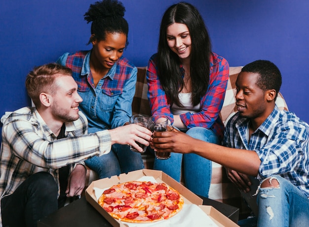 La compagnia internazionale di giovani amici mangia la pizza con la soda, evviva