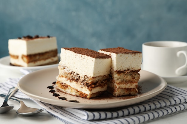 La composizione con tiramisù saporito e la bevanda del cacao sulla tavola di legno bianca. Delizioso dessert