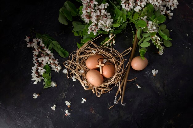 La composizione pasquale Un bouquet con rami di acacia nido e uova in stile vintage su tavola di legno primo piano