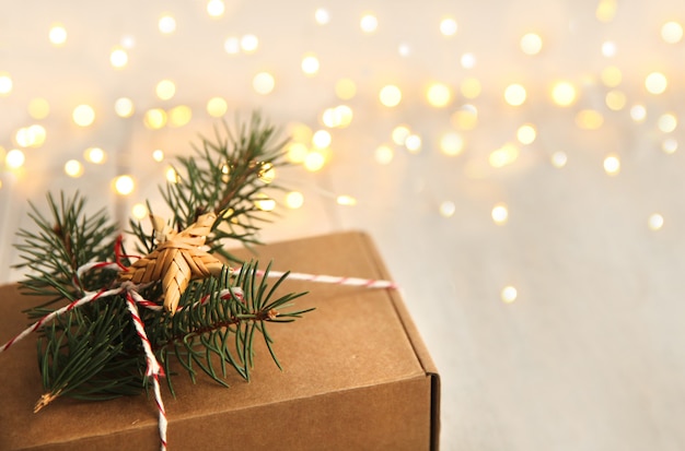 La confezione regalo è decorata con un albero di Natale e una stella di paglia con luci sfocate