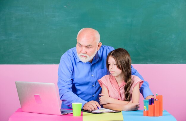 La conoscenza è il potere della tecnologia moderna nell'apprendimento dello shopping scolastico online Scrivere un saggio l'insegnante senior aiuta la ragazza piccola ragazza con l'uomo tutor studio sul laptop istruzione online Ritorno a scuola