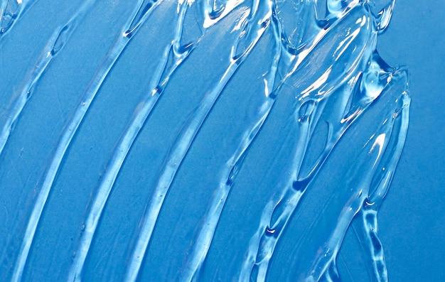 La consistenza di un gel cosmetico trasparente su sfondo blu Prodotto per la cura della pelle igienizzante per le mani