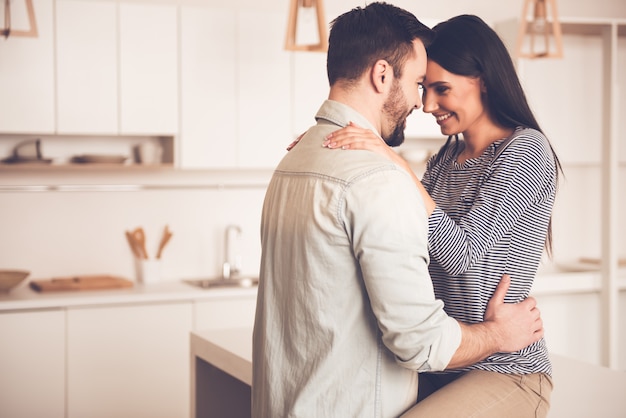 La coppia abbraccia e sorride mentre trascorre del tempo in cucina