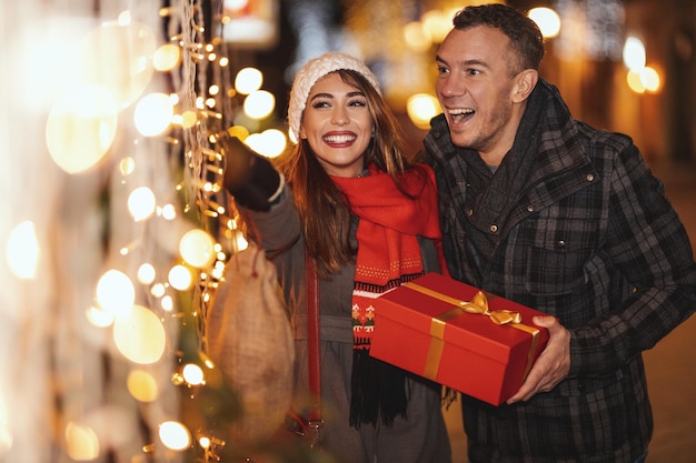 La coppia allegra si diverte per la strada della città la notte di Natale. Il giovane e la donna ridono e comprano regali per i loro cari e l'un l'altro.