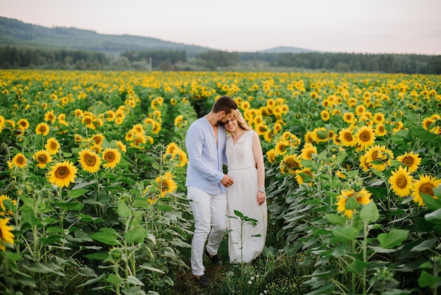 La coppia cammina tra i girasoli in un campo in una giornata estiva