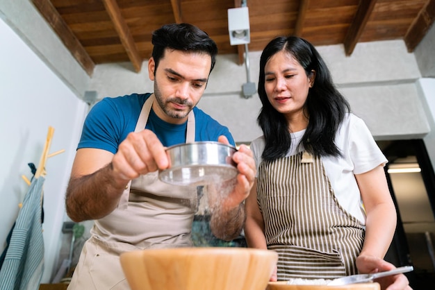 La coppia d'amore prepara la farina per l'impasto per la pizza fatta in casa e il dolce da forno per la torta dolce per il giorno di san valentino