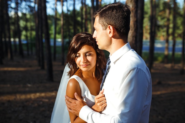 La coppia di sposini felici della sposa e dello sposo sta camminando sulla natura in una foresta verde Concetto di matrimonio