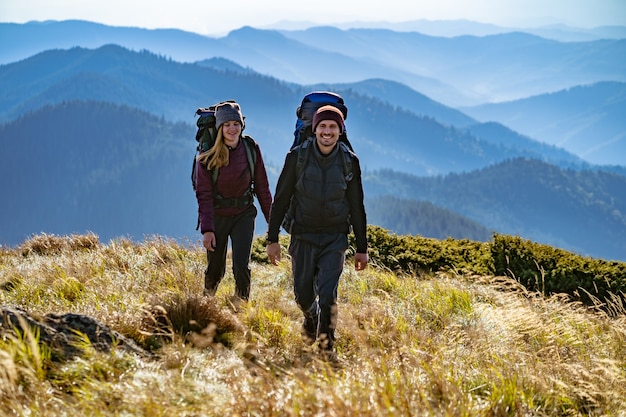 La coppia felice con gli zaini a piedi in montagna