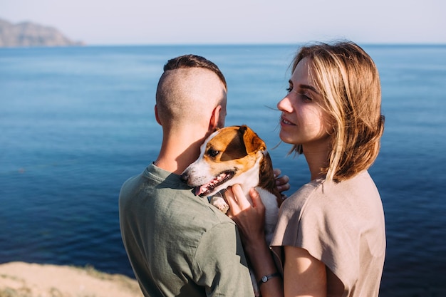 La coppia felice con il giovane e la donna preferiti dell'animale domestico hanno camminato vicino al mare