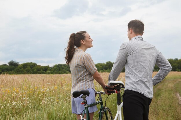 La coppia felice in bicicletta vicino al campo