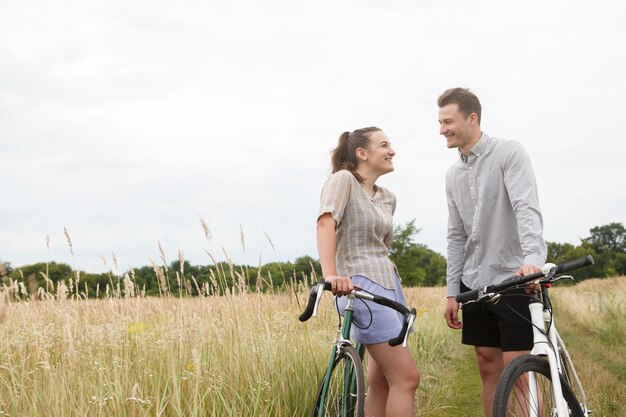 La coppia felice in bicicletta vicino al campo