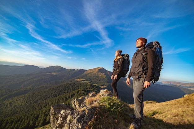 La coppia felice in piedi sulla montagna soleggiata