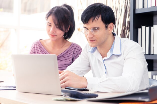 La coppia felice sta utilizzando il computer che lavora insieme a casa