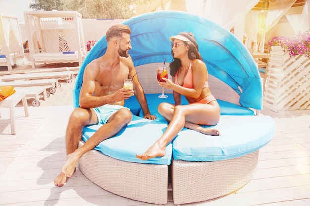 La coppia in costume da bagno beve un cocktail in un posto sulla spiaggia