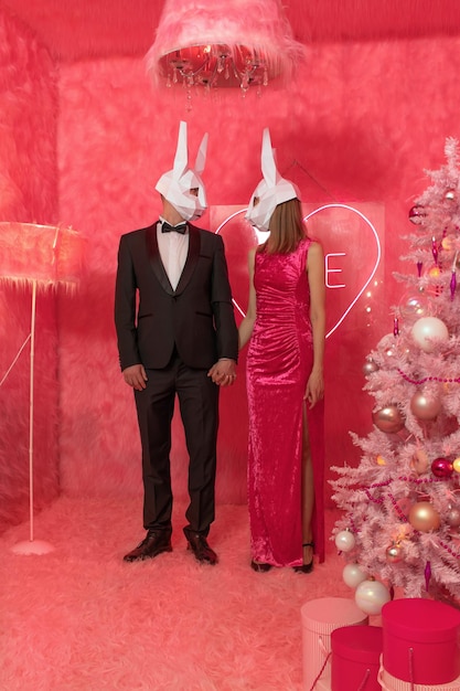 La coppia in maschere poligonali di coniglio in primo piano sullo sfondo rosa festeggia il nuovo anno 2023. C