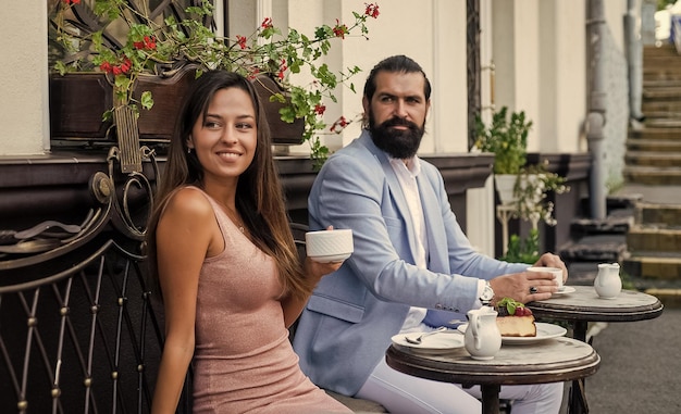 La coppia innamorata beve il caffè del mattino nella caffetteria all'aperto in un appuntamento romantico, l'amore si incontra