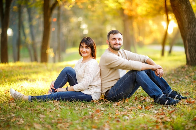 La coppia nell'amore si siede sulle foglie cadute in parco