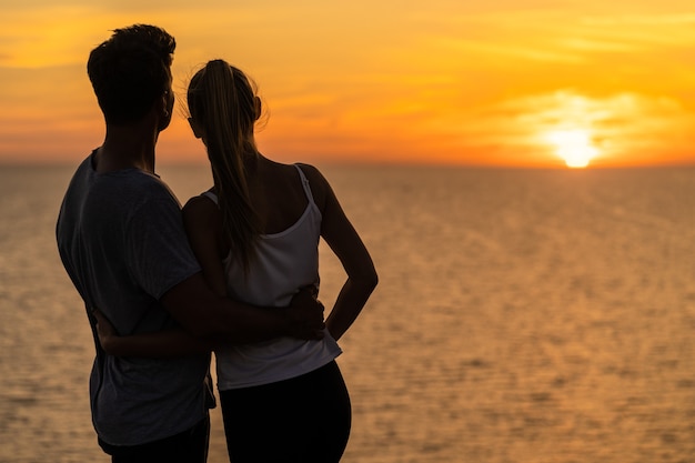 La coppia romantica in piedi vicino al bellissimo sfondo del cielo serale