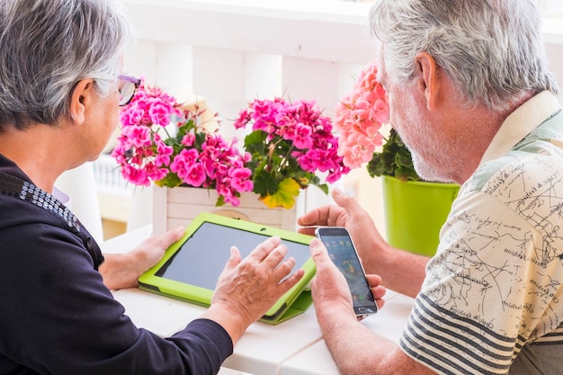 la coppia senior adulta usa il computer portatile per il tempo libero all'aperto sulla terrazza di casa. sorridi e goditi il bel tempo e la vita ritirata stando insieme tutti i giorni senza lavoro. usa la tecnologia per restare