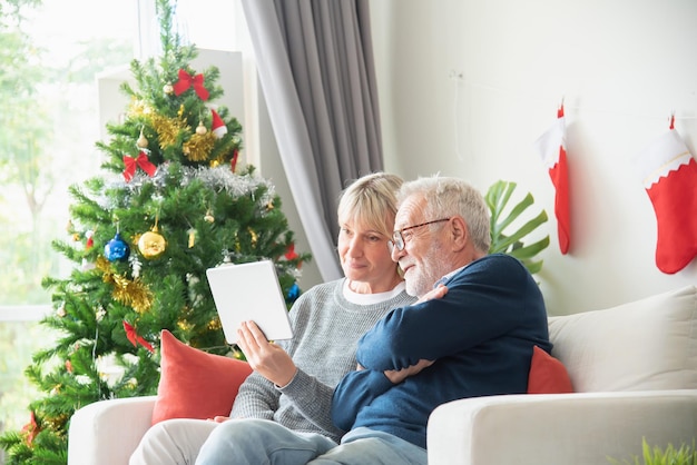 La coppia senior si è seduta e ha guardato il tablet in soggiorno con un albero di Natale